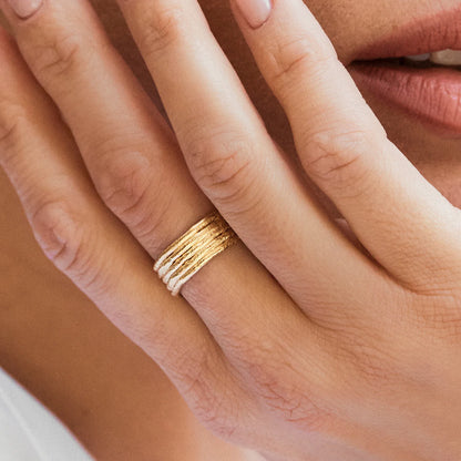 Close-up of a hand wearing a gold ring with a blurred background