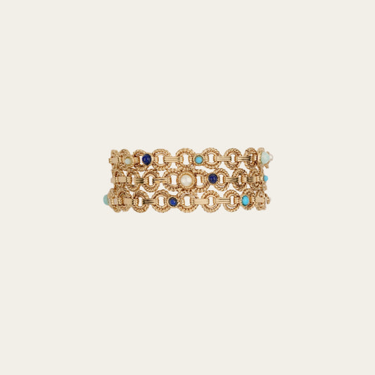Gold bracelet with blue and turquoise stones on a beige background
