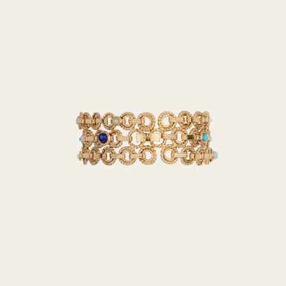 Gold chain bracelet with blue and turquoise stones on a beige background