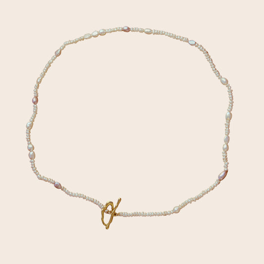 Pearl necklace with a gold clasp on a brown background