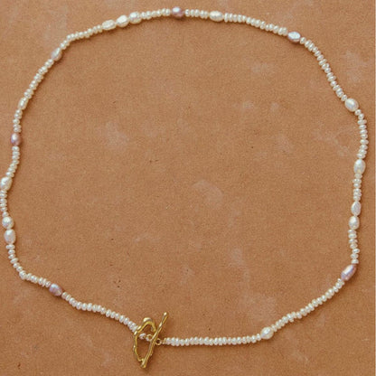 Pearl necklace with a gold clasp on a brown background