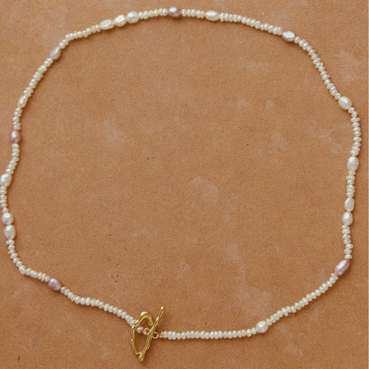 Pearl necklace with a gold clasp on a brown background