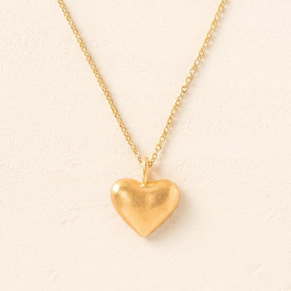Gold heart-shaped pendant necklace on a beige background