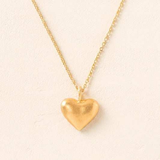 Gold heart-shaped pendant necklace on a beige background