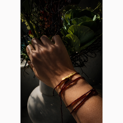 Hand with bracelets holding a bouquet of flowers against a dark background