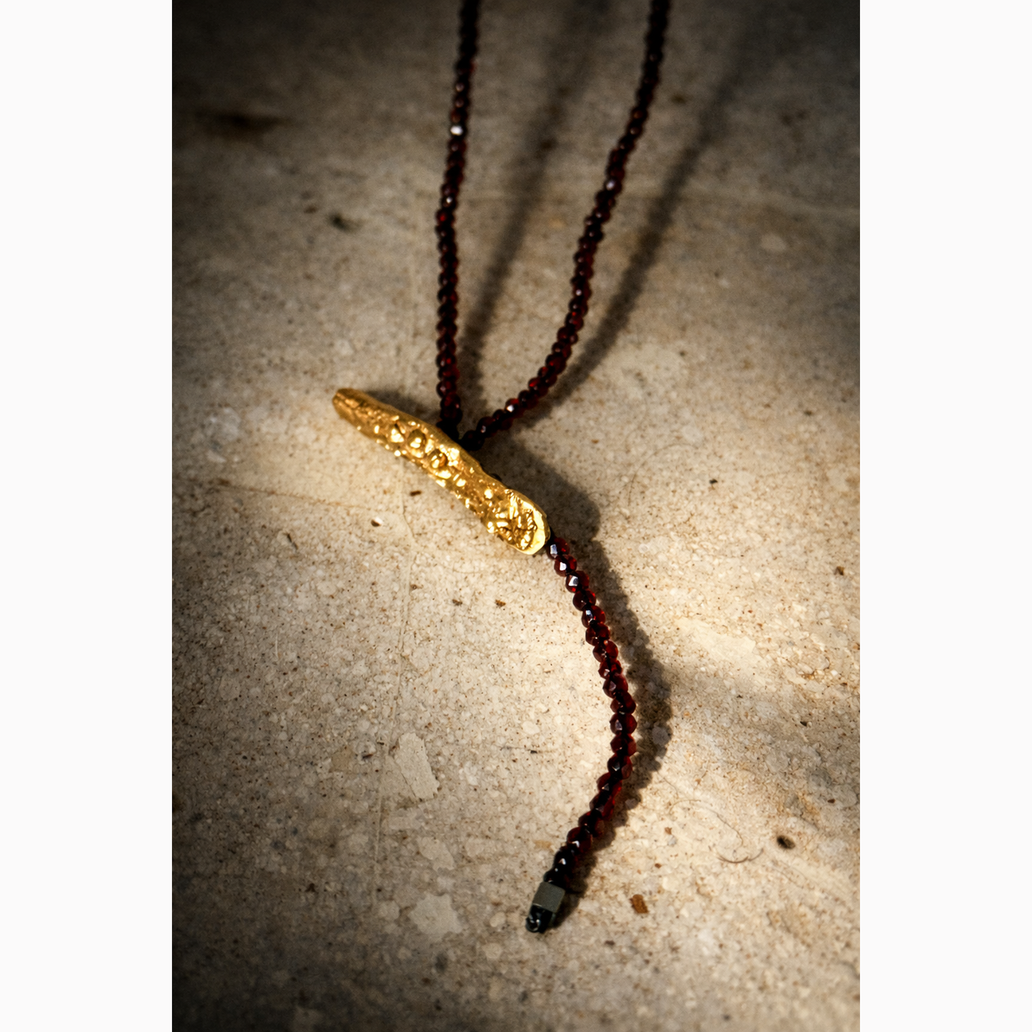 Necklace with a gold clasp and dark beads on a textured surface