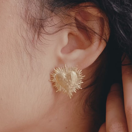 video of close up of womans ear and godld heart earring