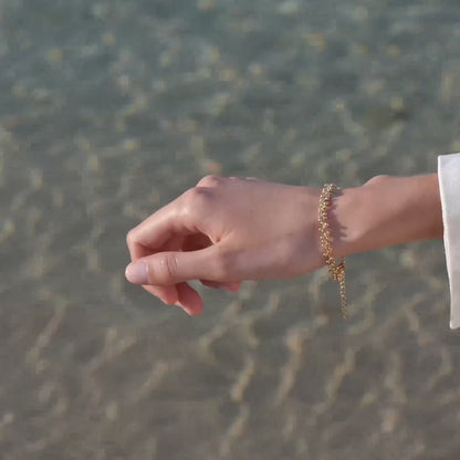 gold bracelet on models hand at beach