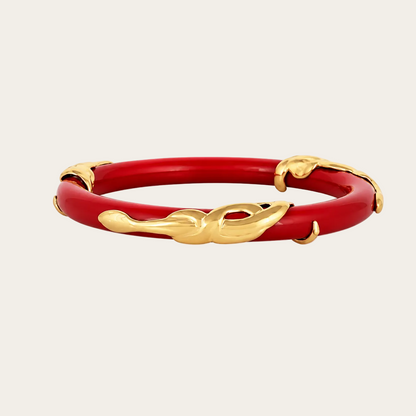 A red bangle bracelet with gold-toned decorative accents, photographed on a clean white background.
