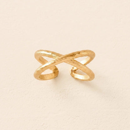 Gold ring with a unique design on a beige background