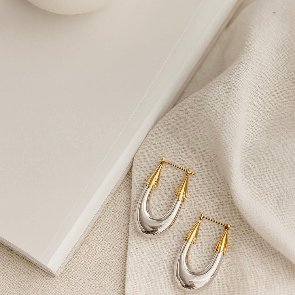Gold and silver hoop earrings on a beige fabric surface