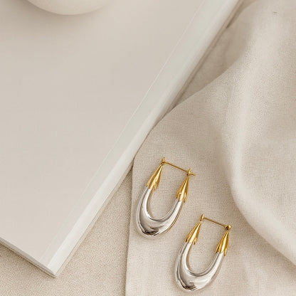 Gold and silver hoop earrings on a beige fabric surface