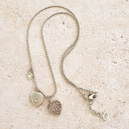Silver necklace with heart-shaped pendants on a sandy surface