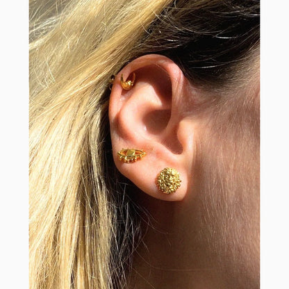 Close-up of an ear wearing gold earrings with blonde hair.