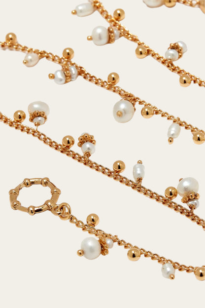 Gold chain necklace with pearls on a white background
